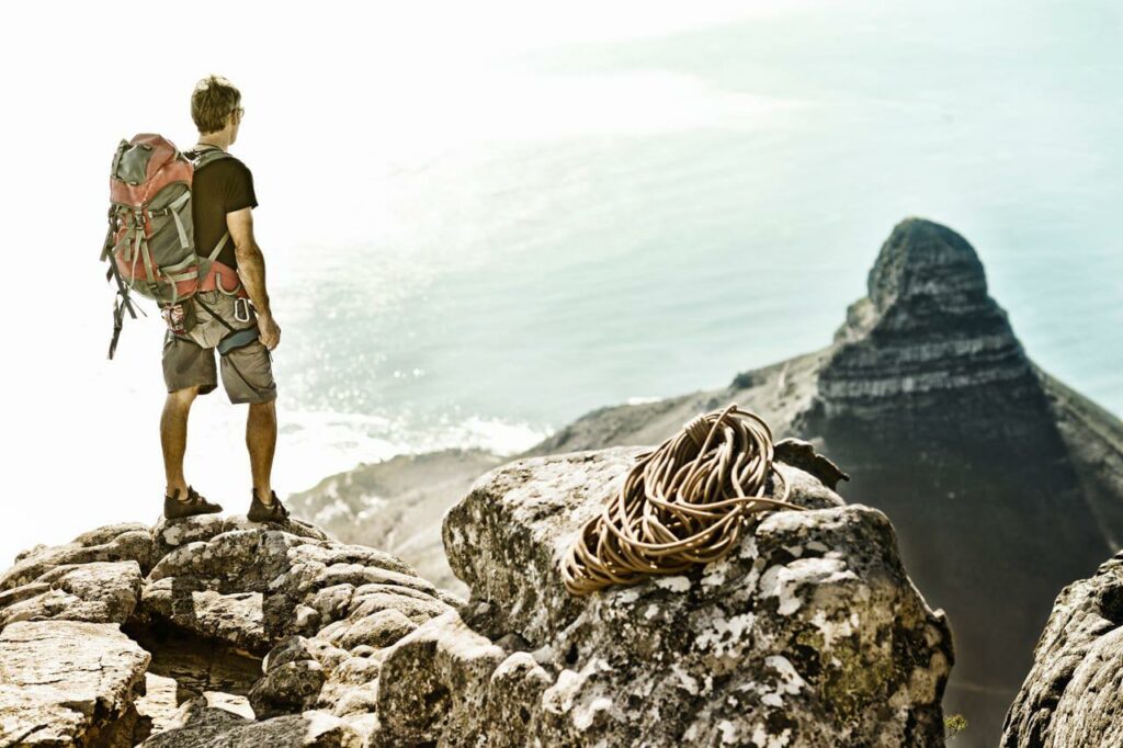 Hiker carrying a backpack at the top of Table Mountain with Lions Head in the background